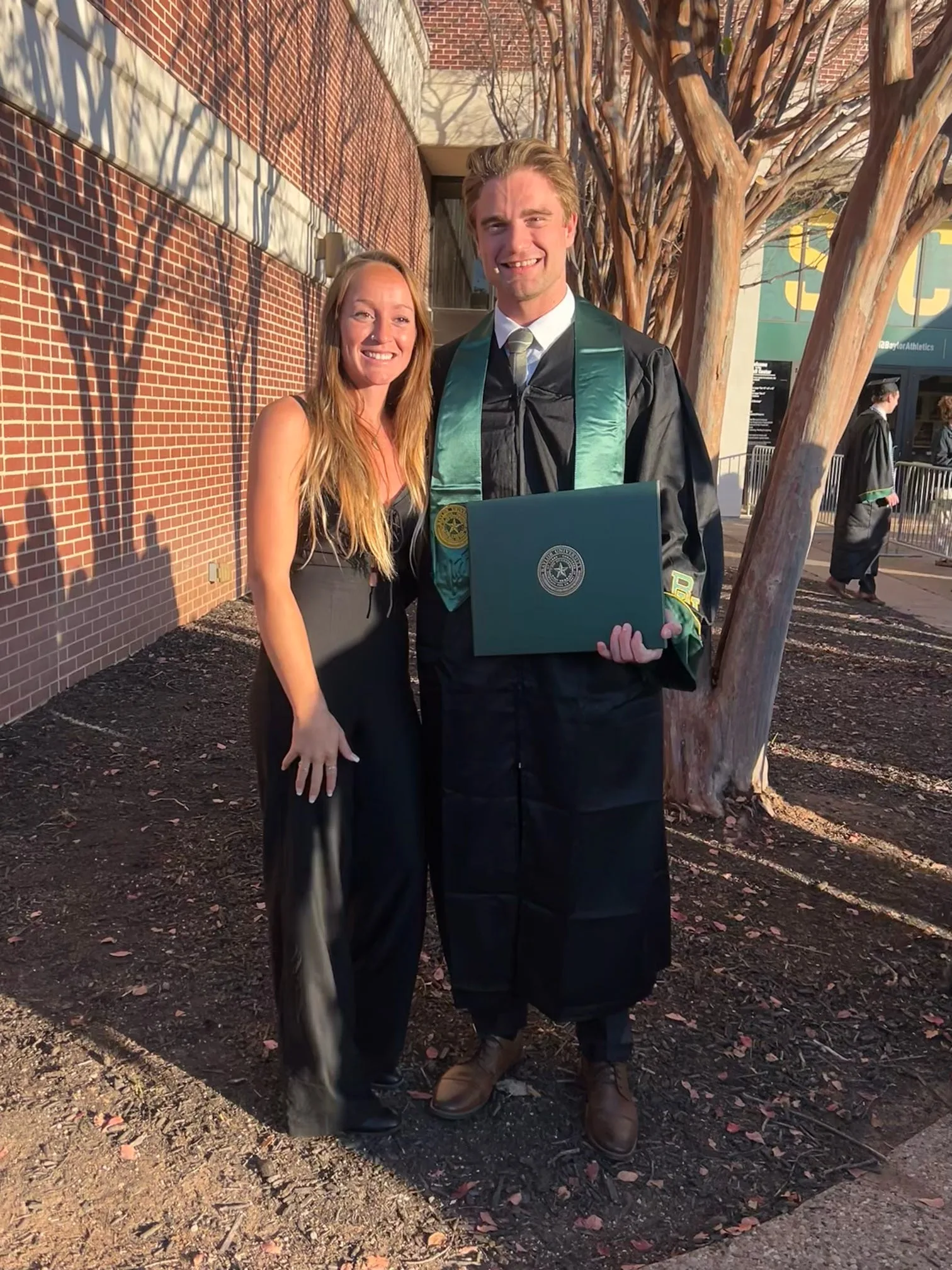 Logan on graduation day at Baylor, holding his diploma