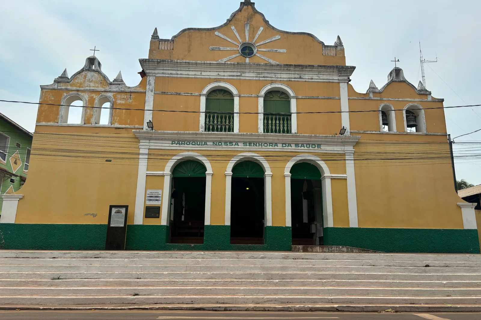 The yellow and green front of the village church in Alter do Chão, three arched doors under a curved gable and two small towers, at the top of a flight of steps