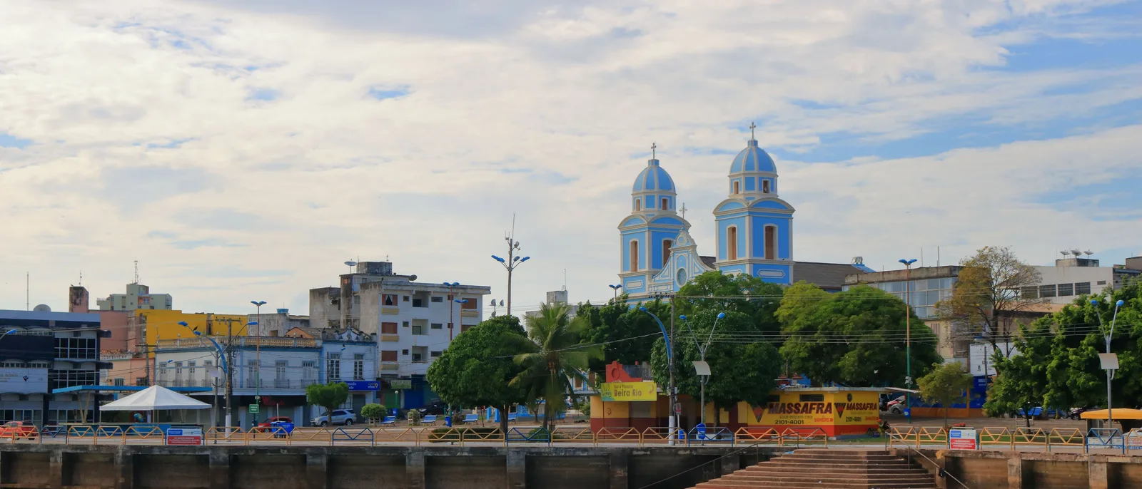 The Santarém waterfront from the quay: a pale blue cathedral with twin domed towers behind trees and a row of low buildings