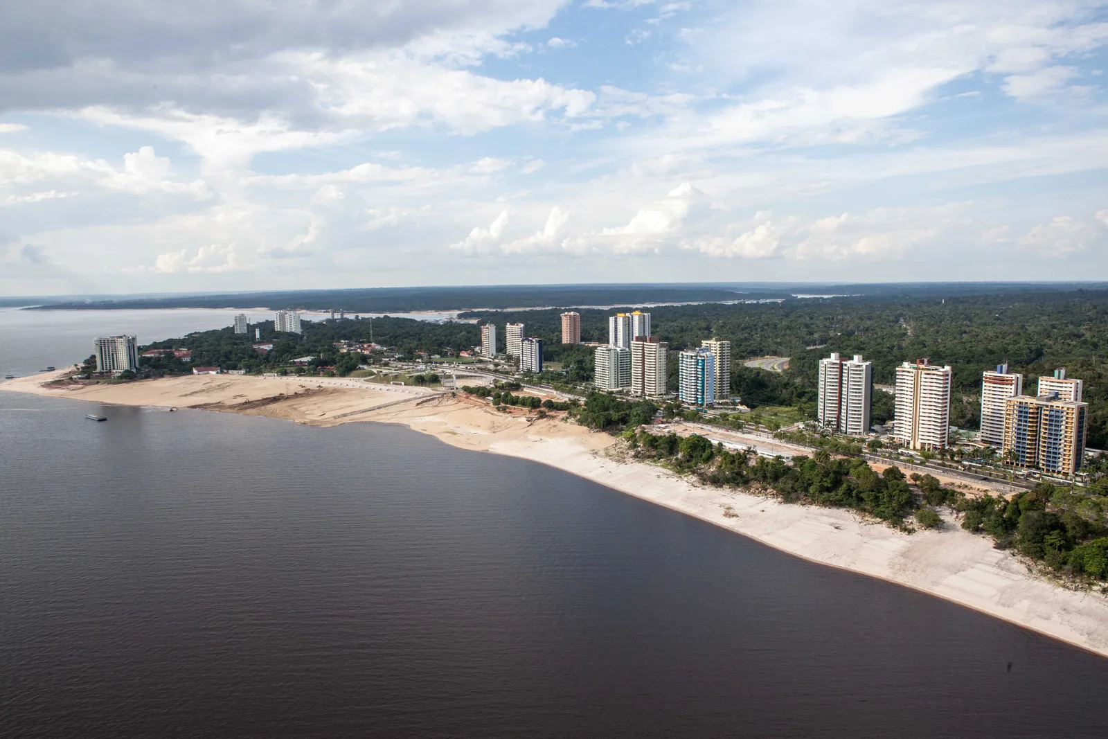 Ponta Negra from the air: a pale river beach curving along the shore with a line of apartment towers behind it