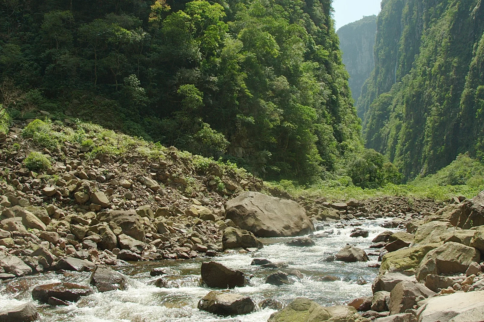 A rocky river running between steep forested canyon walls on the Rio do Boi trail
