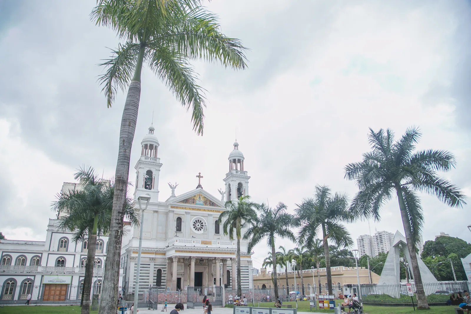 The Basílica de Nazaré seen across its square: a white church with twin bell towers and a domed crossing, framed by tall palms