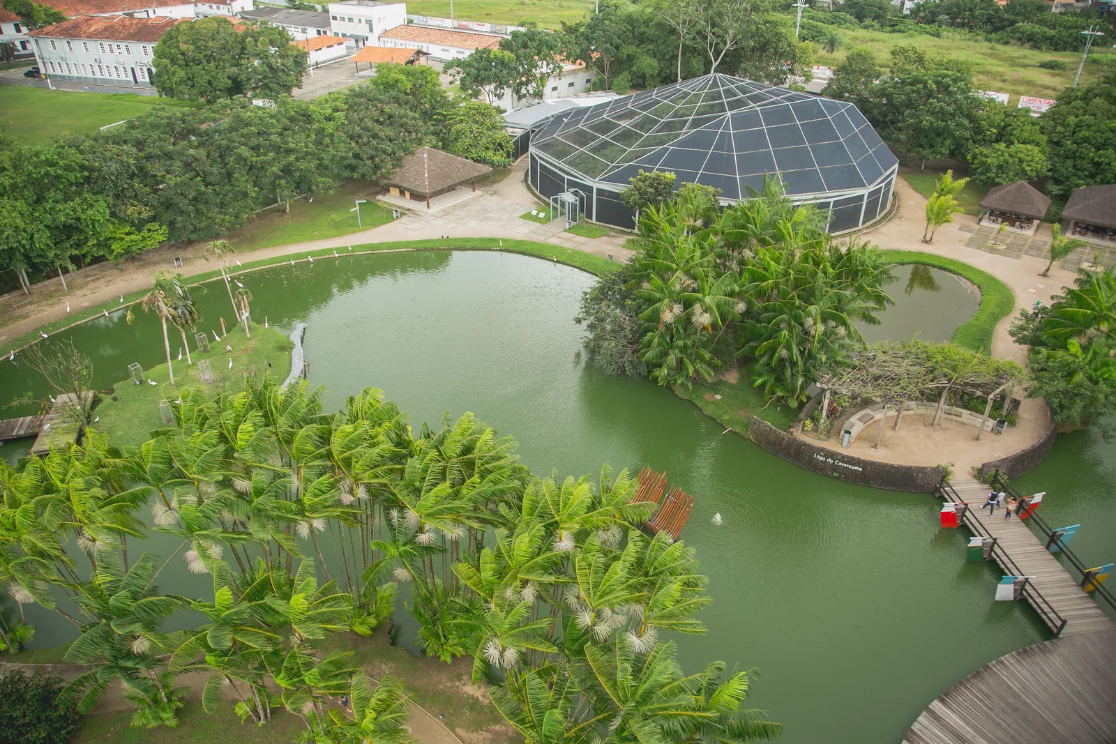 The Mangal das Garças from above: a still green lake with a domed glass butterfly house on its bank, lawns, palms and thick planting all around it
