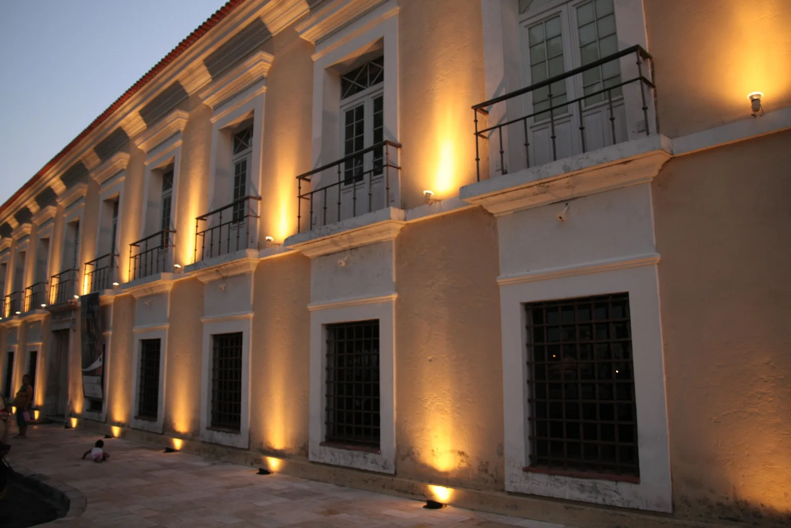 The Casa das Onze Janelas floodlit warm gold after dark, its long row of tall shuttered windows and iron balconies lit from below