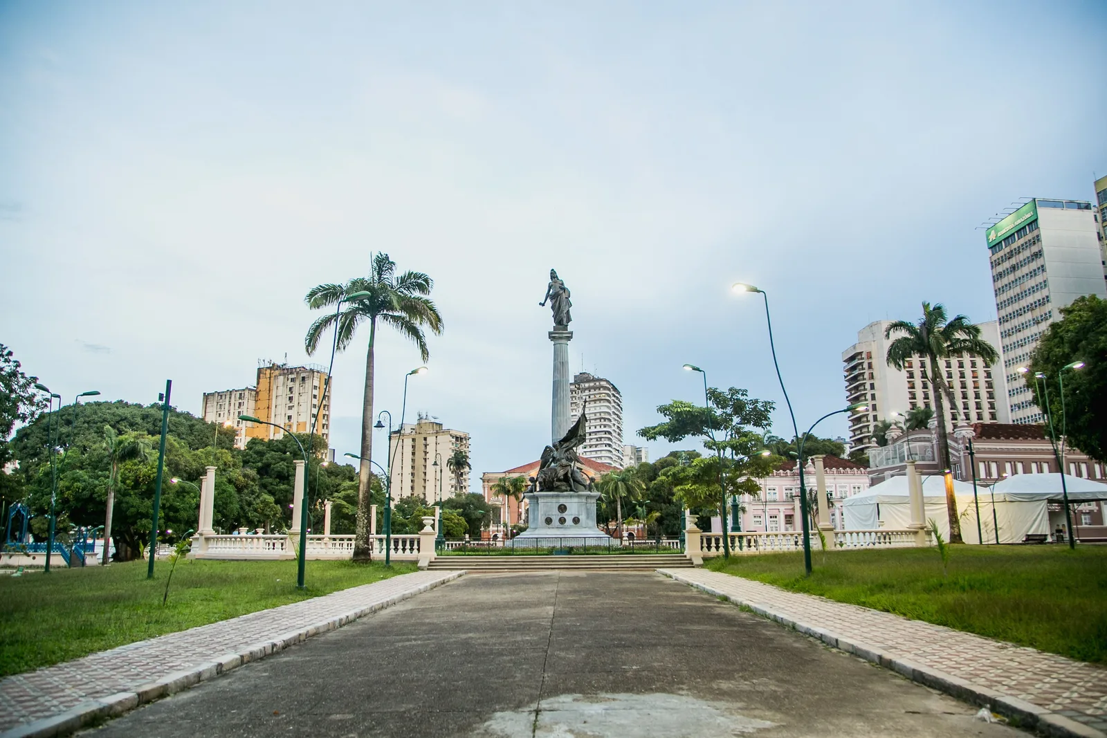 The Praça da República in Belém: a wide paved avenue between clipped hedges leading to a tall stone monument, palms and city buildings behind