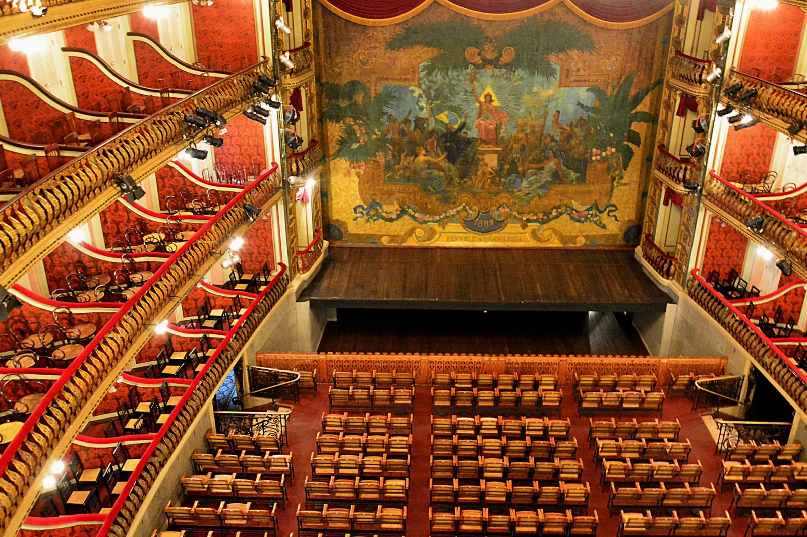 The auditorium of the Theatro da Paz from the upper tier: rows of seats on the floor below, gilded boxes curving around the walls and a large painted panel above the stage