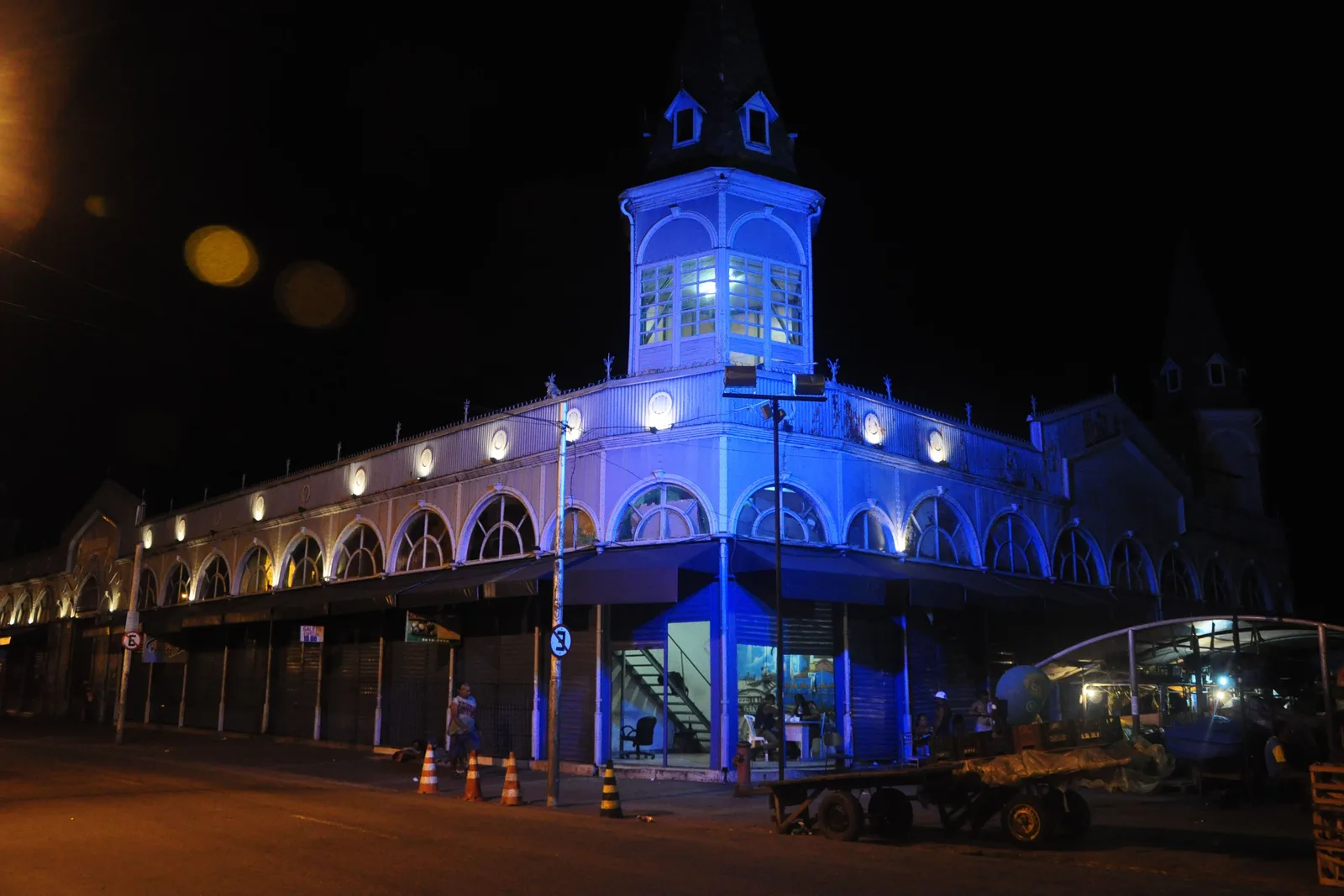 The Ver-o-Peso market pavilion lit deep blue after dark, its arcade of arches and its glazed corner turret picked out against a black sky