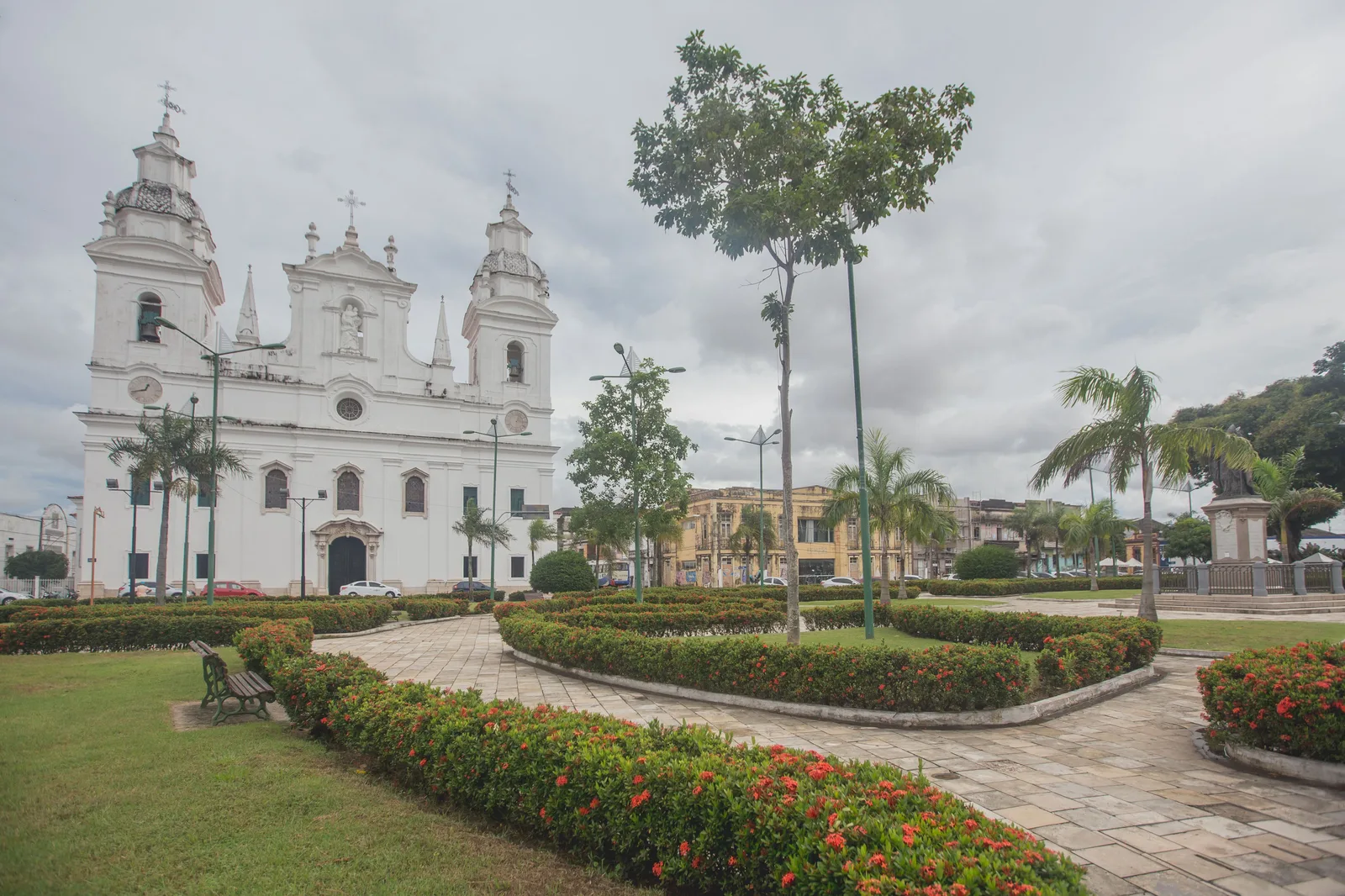 The Catedral da Sé in Belém across its garden square: a white twin-towered church behind clipped hedges and flowerbeds under a heavy gray sky