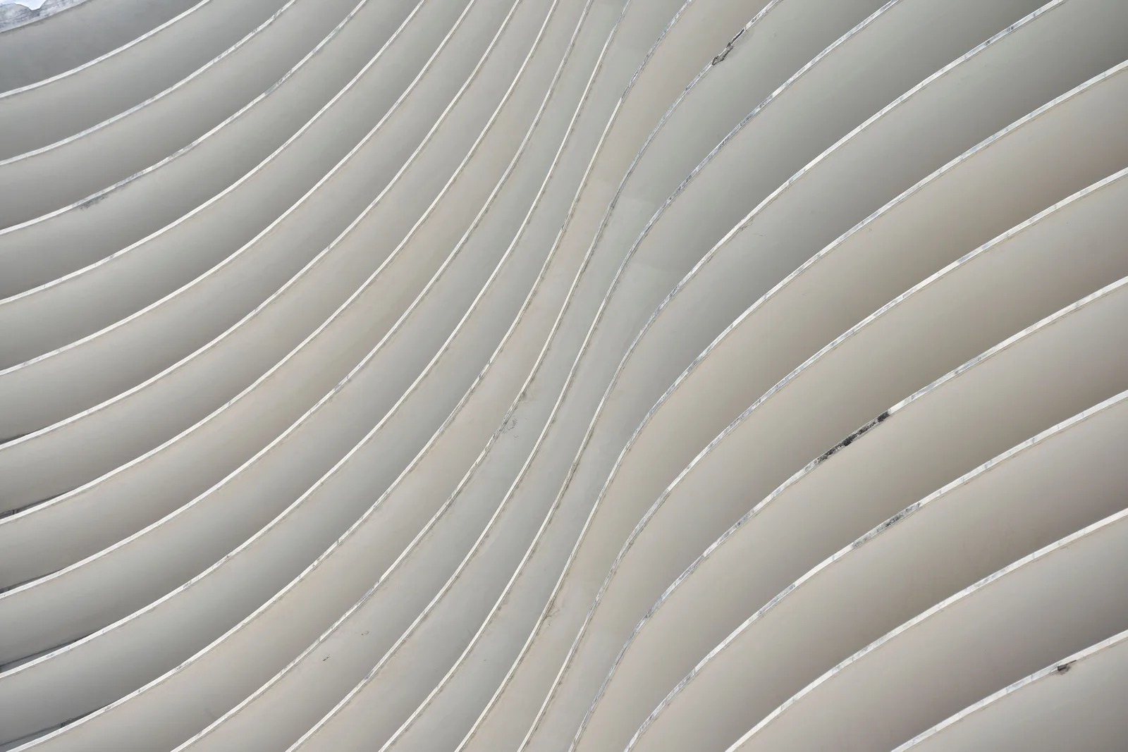 A close crop of the curving horizontal bands of the Edifício Niemeyer facade, pale concrete lines sweeping across the whole frame