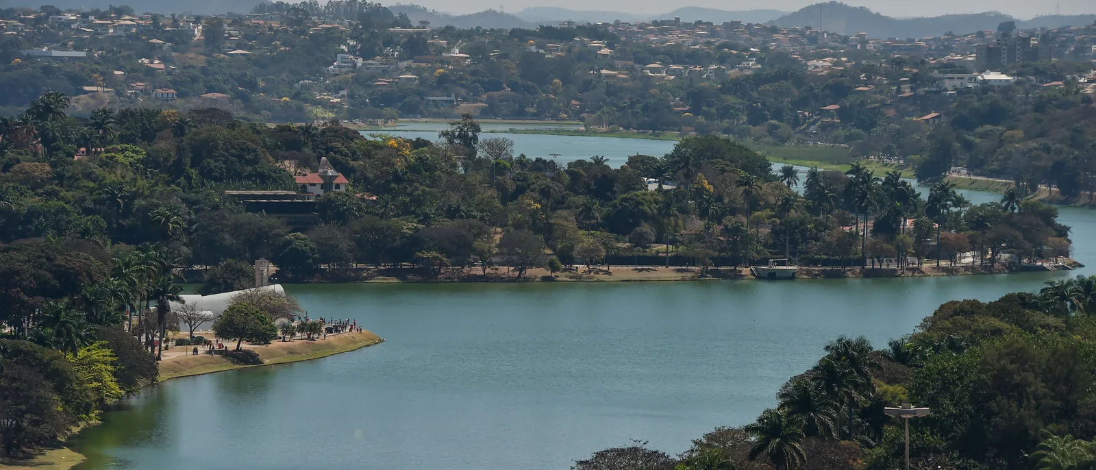 The Pampulha lake from a height, wooded shores and a small headland running out into the water, low hills on the horizon