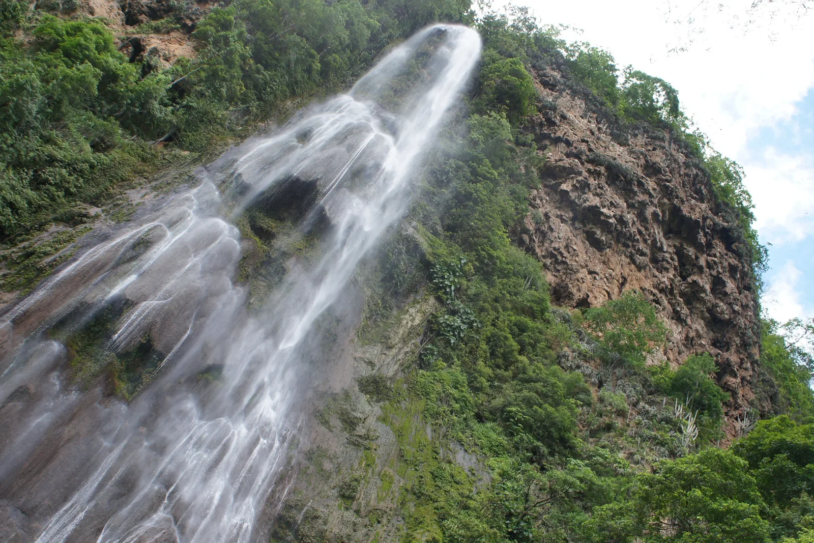 A tall waterfall dropping in a broad white plume down a pale rock face in the Bodoquena canyon country, with green forest crowding both sides of it