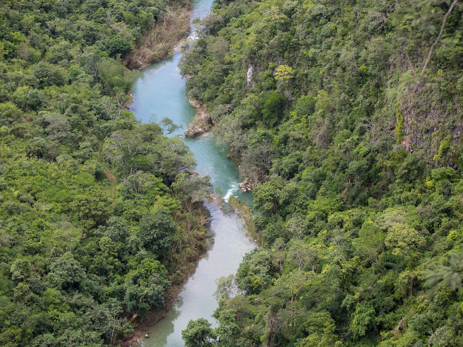 An aerial view of a turquoise river running through a steep, densely forested canyon in the Serra da Bodoquena