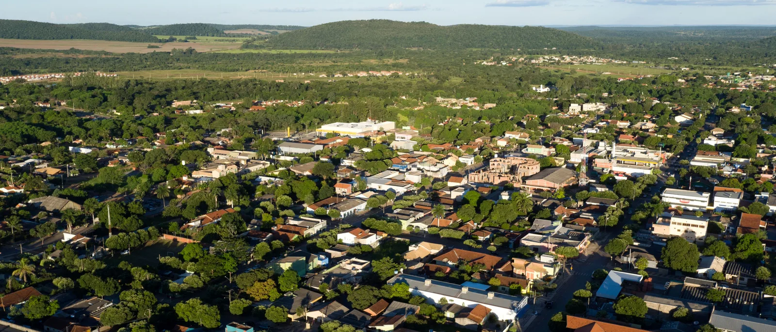 Bonito from the air: a grid of low houses and red roofs under heavy street trees, with green countryside and low hills running away behind the town