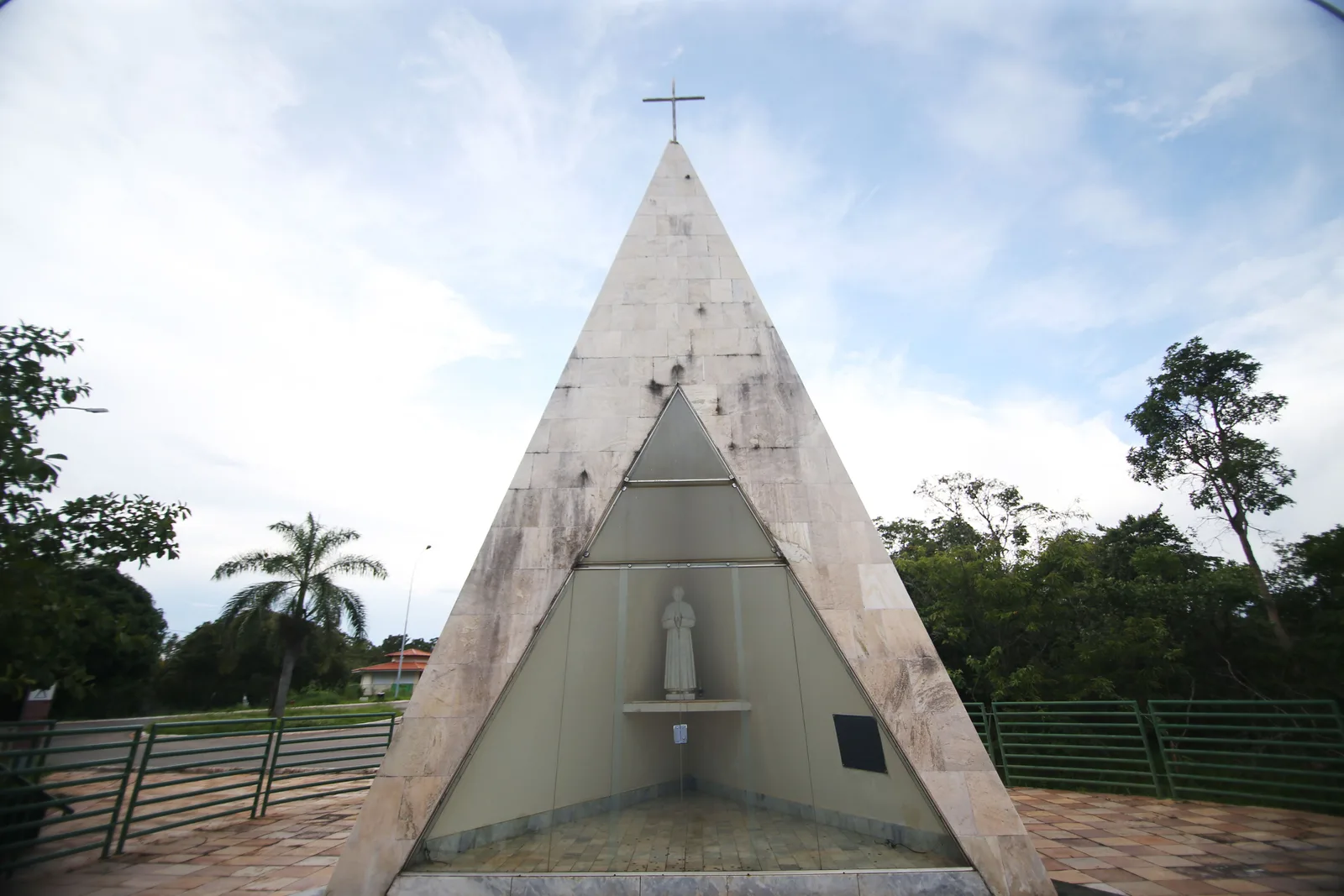 The Ermida Dom Bosco: a small marble pyramid chapel with a cross on top and a statue of Dom Bosco behind its glass front, on a paved terrace among trees