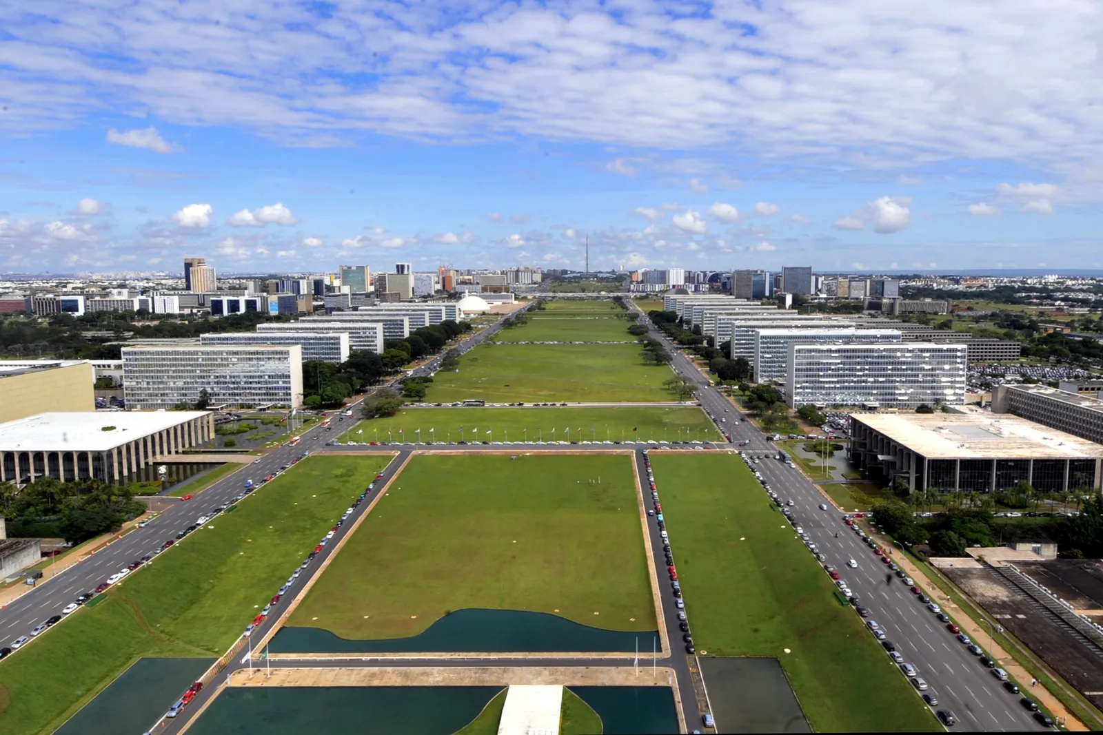 The Eixo Monumental from high above on a clear day: long green lawns and pools running between two rows of low government blocks, the city spreading to the horizon