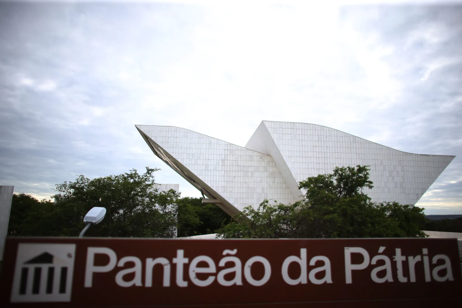 The white folded-concrete roof of the Panteão da Pátria in the Praça dos Três Poderes, its name in large letters on a sign in the foreground