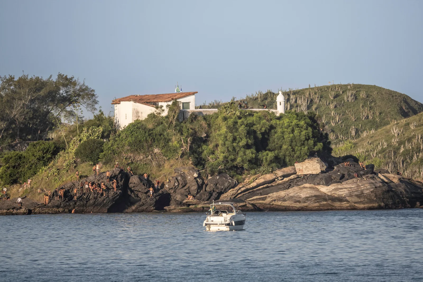 The Forte São Mateus at Cabo Frio seen from the water: a low white fort on a rocky cactus-covered headland with the sea in front of it