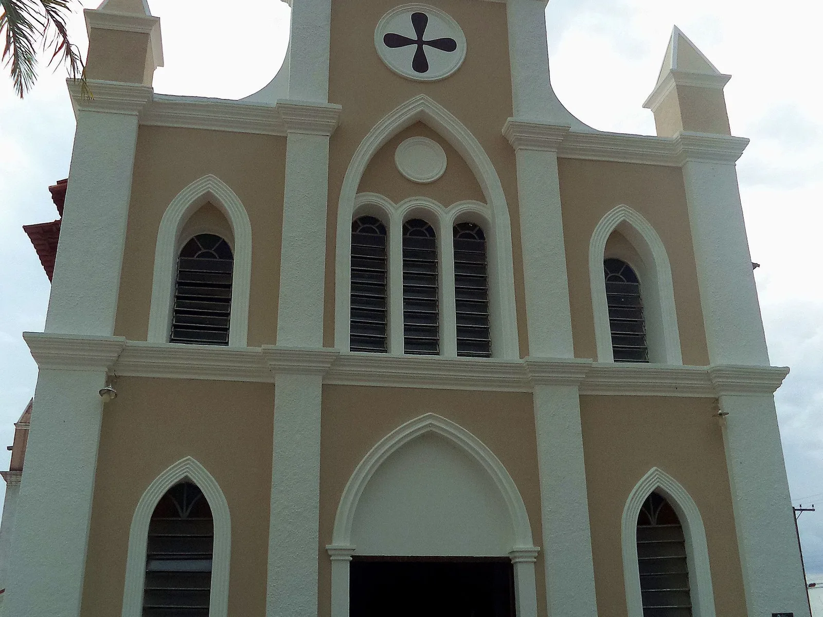 The cream and beige facade of the cathedral of São Pedro de Alcântara in Carolina, with pointed windows and a small rose window, seen from below
