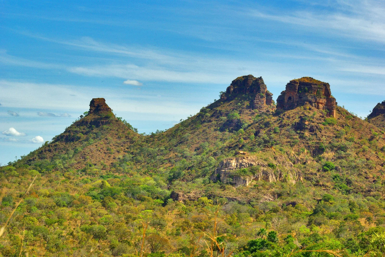 Green hills topped with knobs of bare rock under a blue sky streaked with thin cloud
