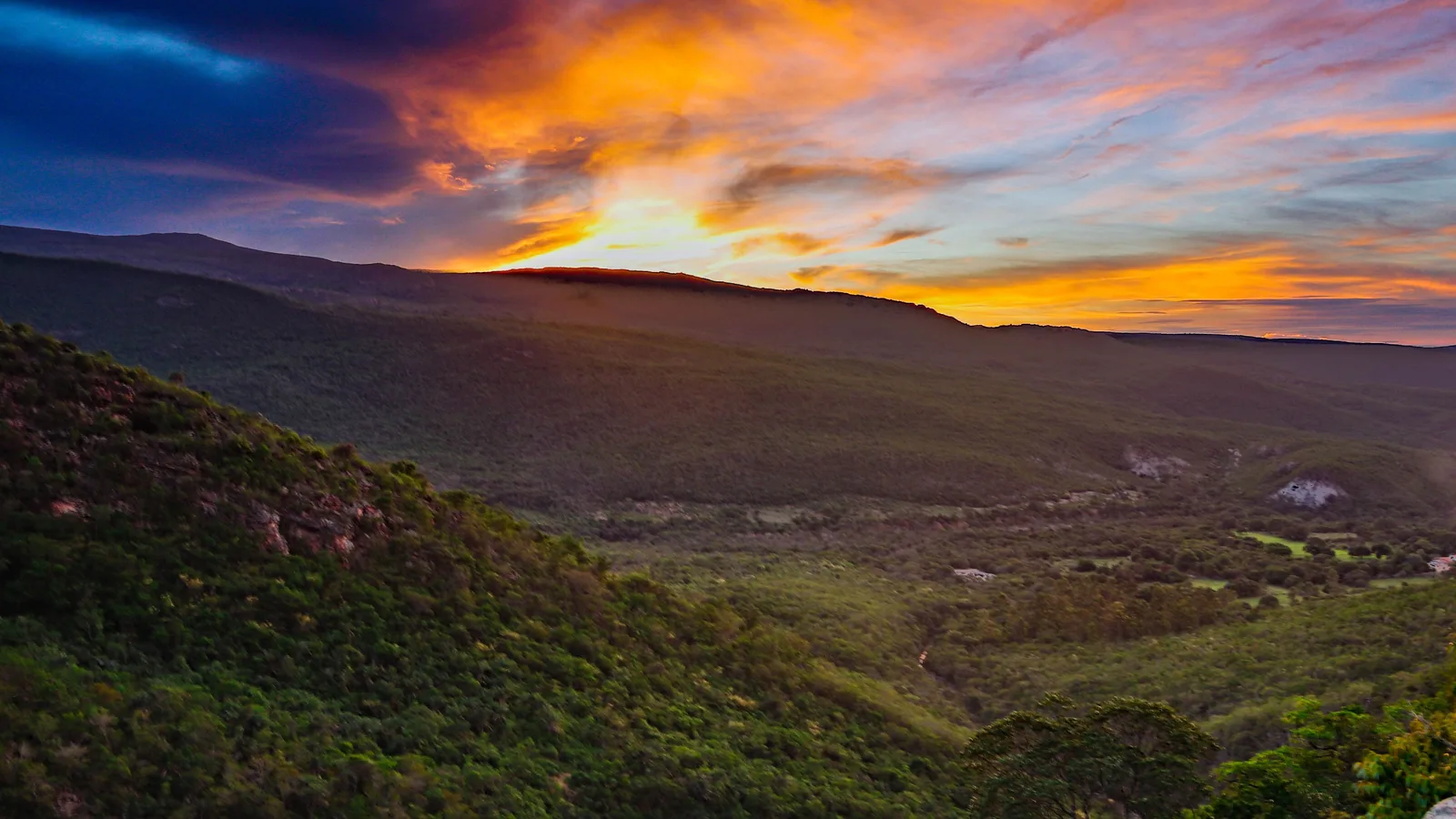An orange and purple sunset over the Vale do Capão, the ridgelines dark against the sky