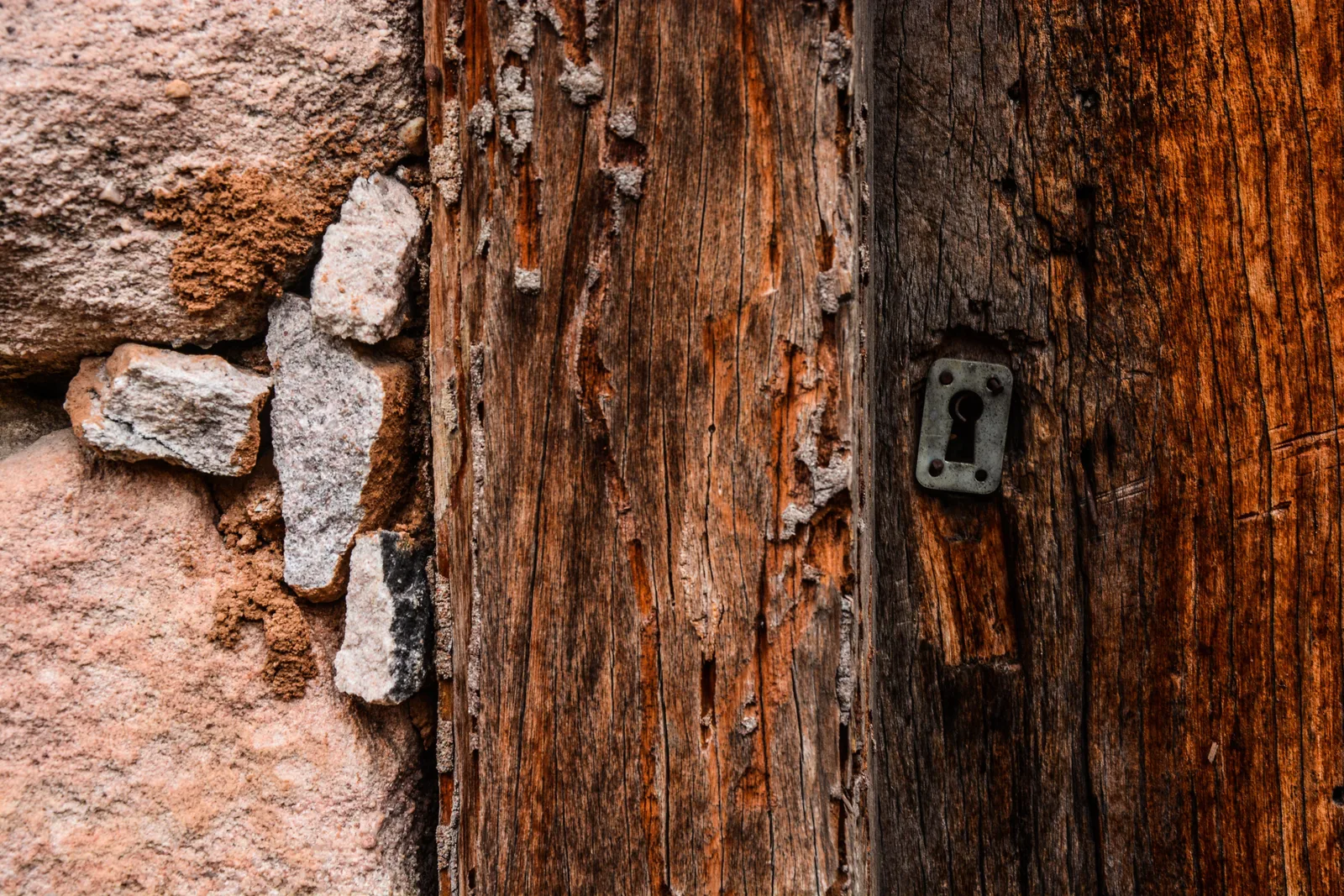 An old wooden door with a keyhole escutcheon plate, set into a wall of dry-laid stone at Igatu