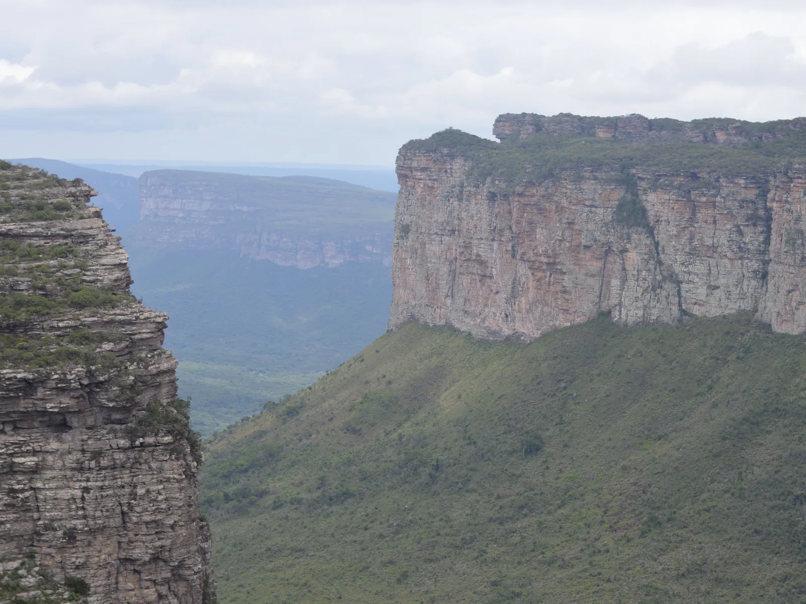 Flat-topped mountains standing across a green valley, seen from the summit of Morro do Pai Inácio