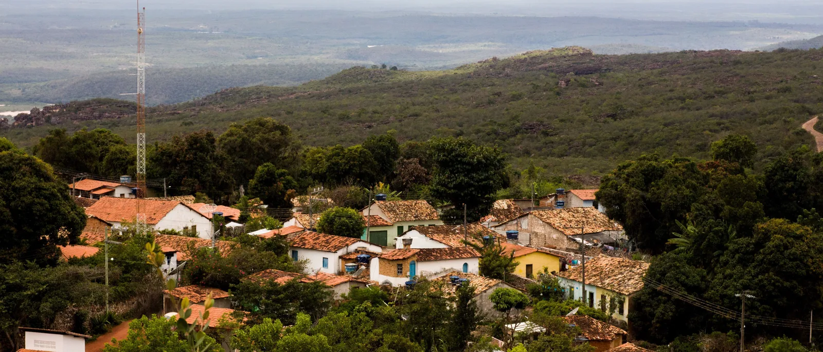 The village of Igatu from above, red-tiled roofs among trees on a rock shelf with open country running away behind