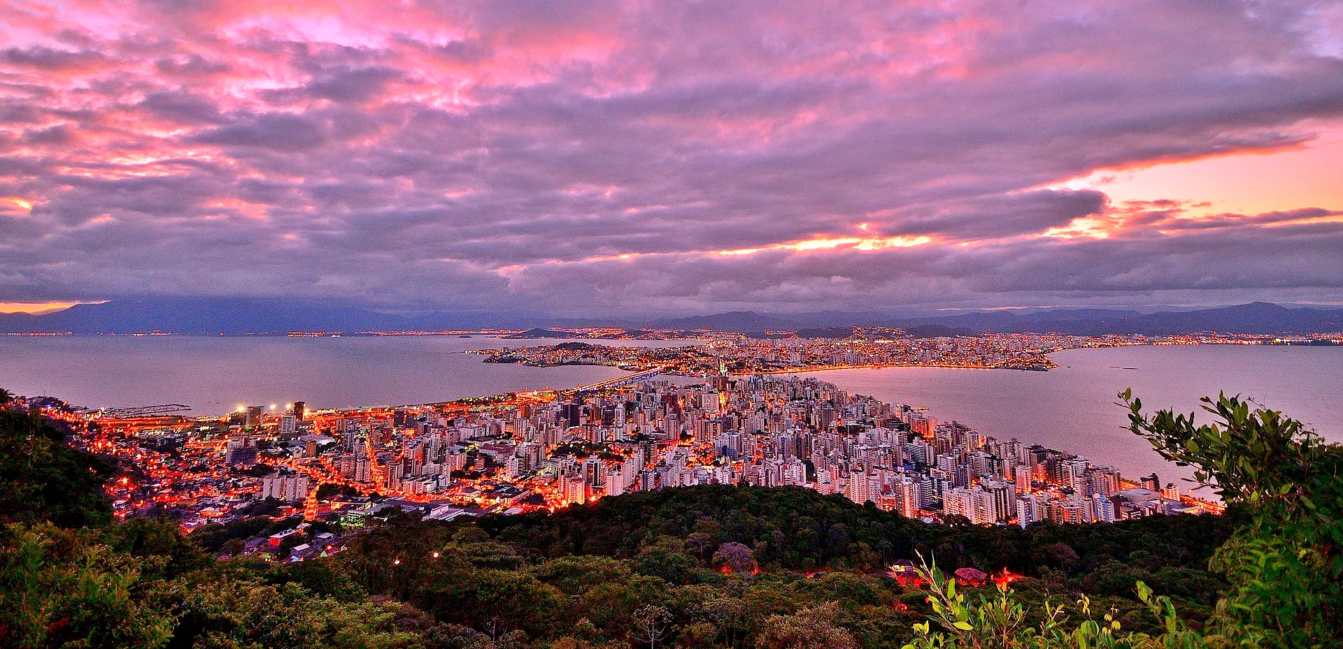 Wide aerial view over Florianópolis island: green coastline, beaches and blue ocean