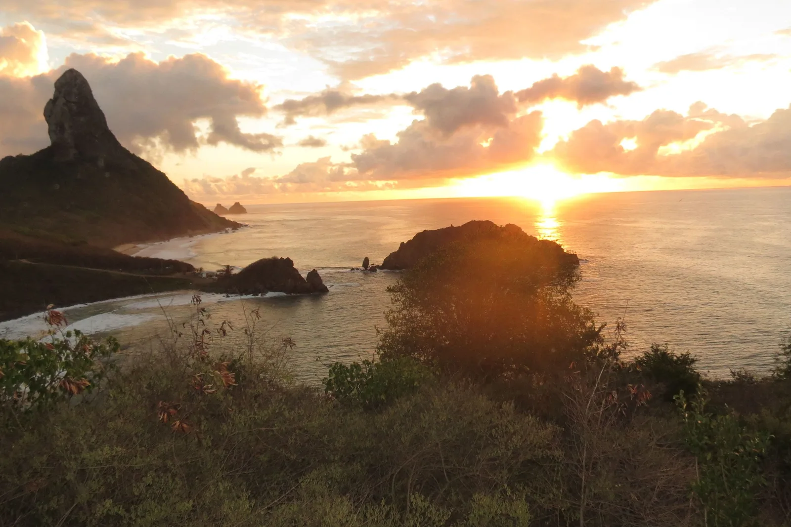 Sunset over the sea from the fort above the village, the pointed silhouette of Morro do Pico on the left and a low rock island catching the last light
