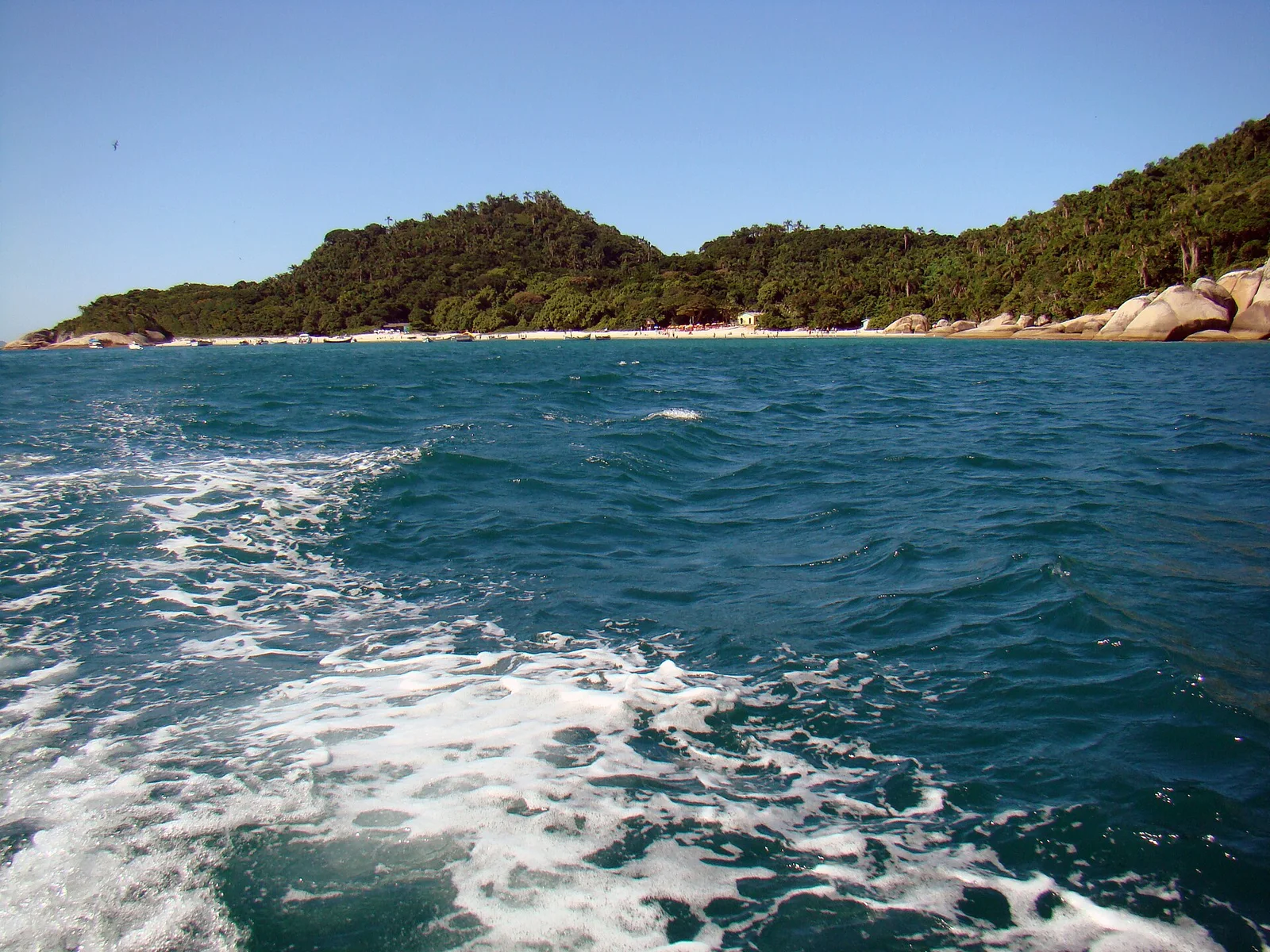 Ilha do Campeche seen across the boat’s wake on the crossing over, its forested slopes and pale beach ahead