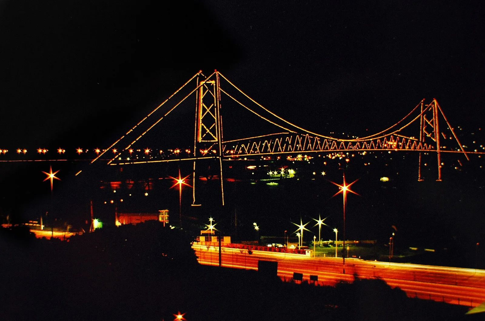 The Hercílio Luz bridge lit up after dark, its steel span picked out in warm light above the waterfront