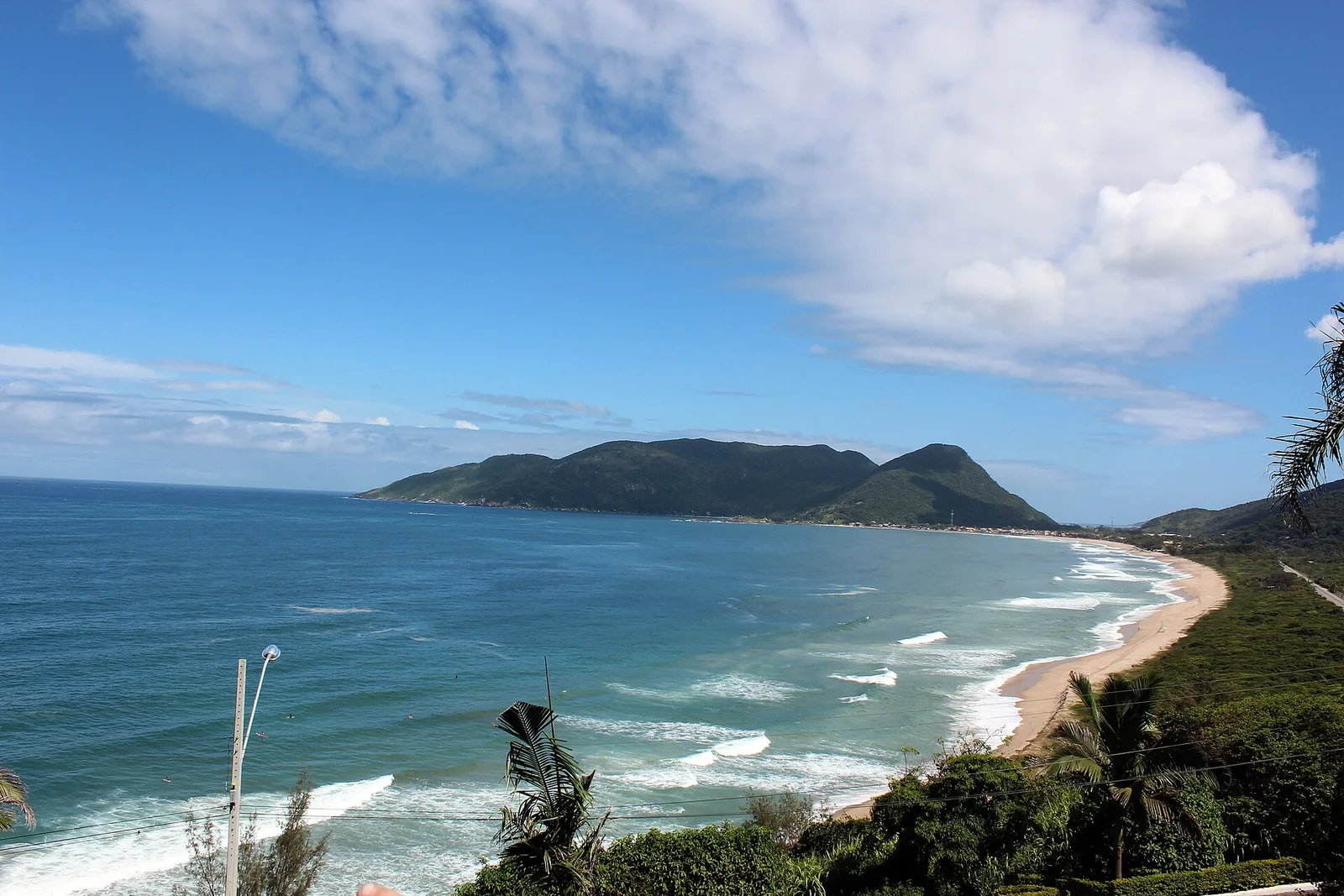 The long curve of Praia Brava seen from the headland above, forested hills running down to the surf