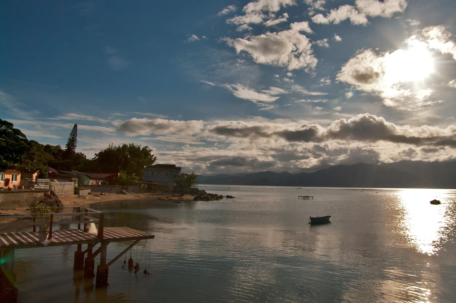 Golden-hour light over the calm channel at Ribeirão da Ilha, colorful houses and a small boat on the water
