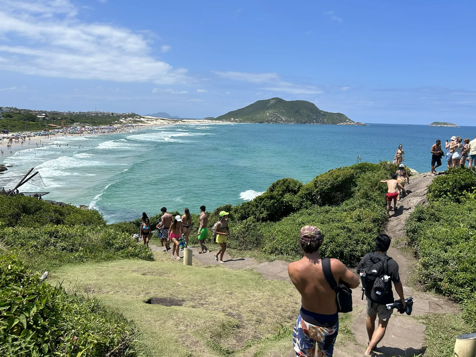 A footpath along a green headland leading down to Praia do Santinho in Florianópolis