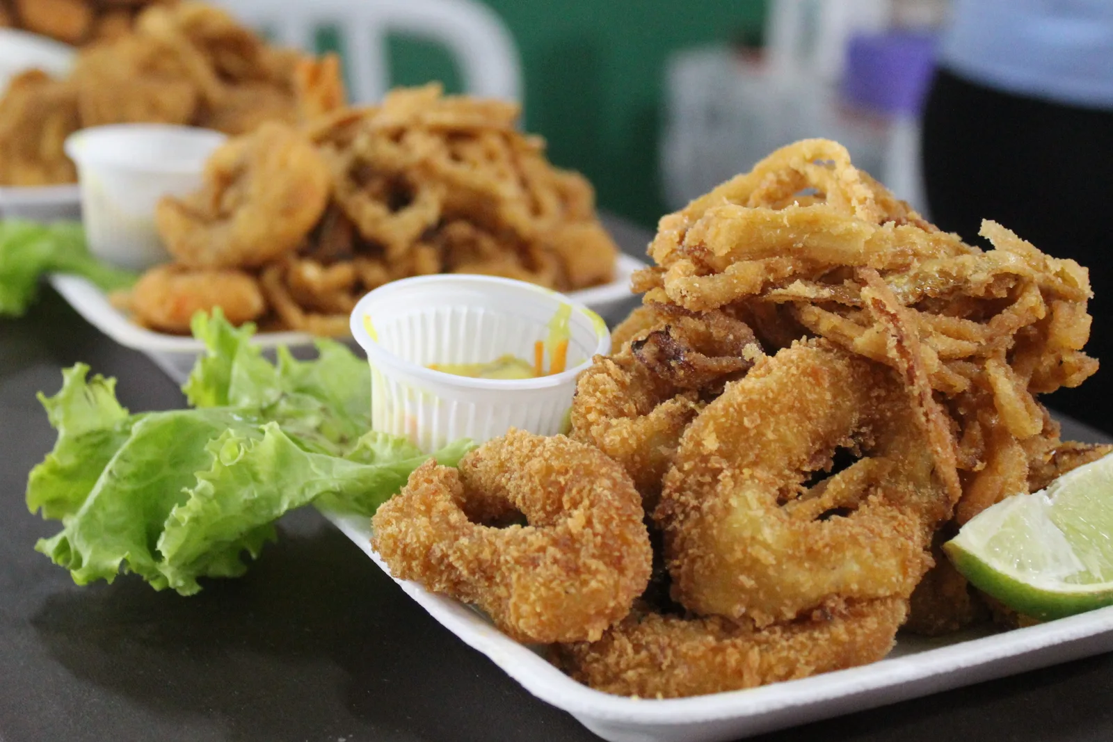 Several plates of breaded and fried shrimp with lime, brought out one after another in the style of a sequência de camarão