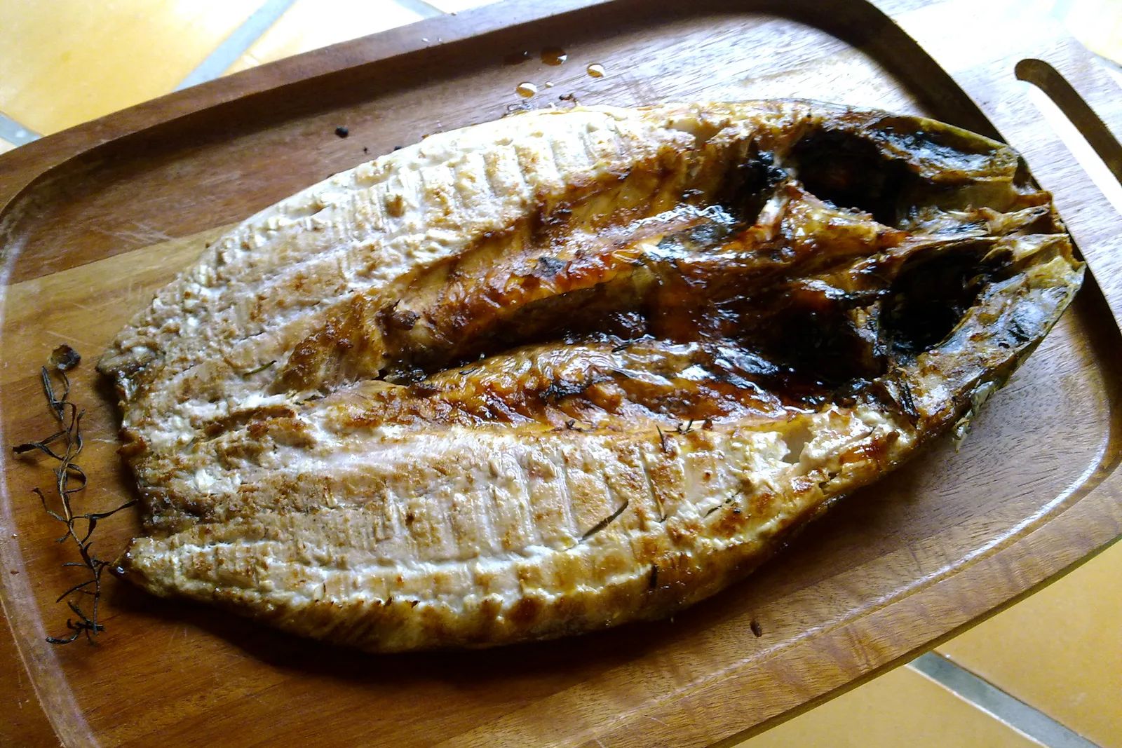 A whole split tainha (mullet), grilled and served on a wooden board