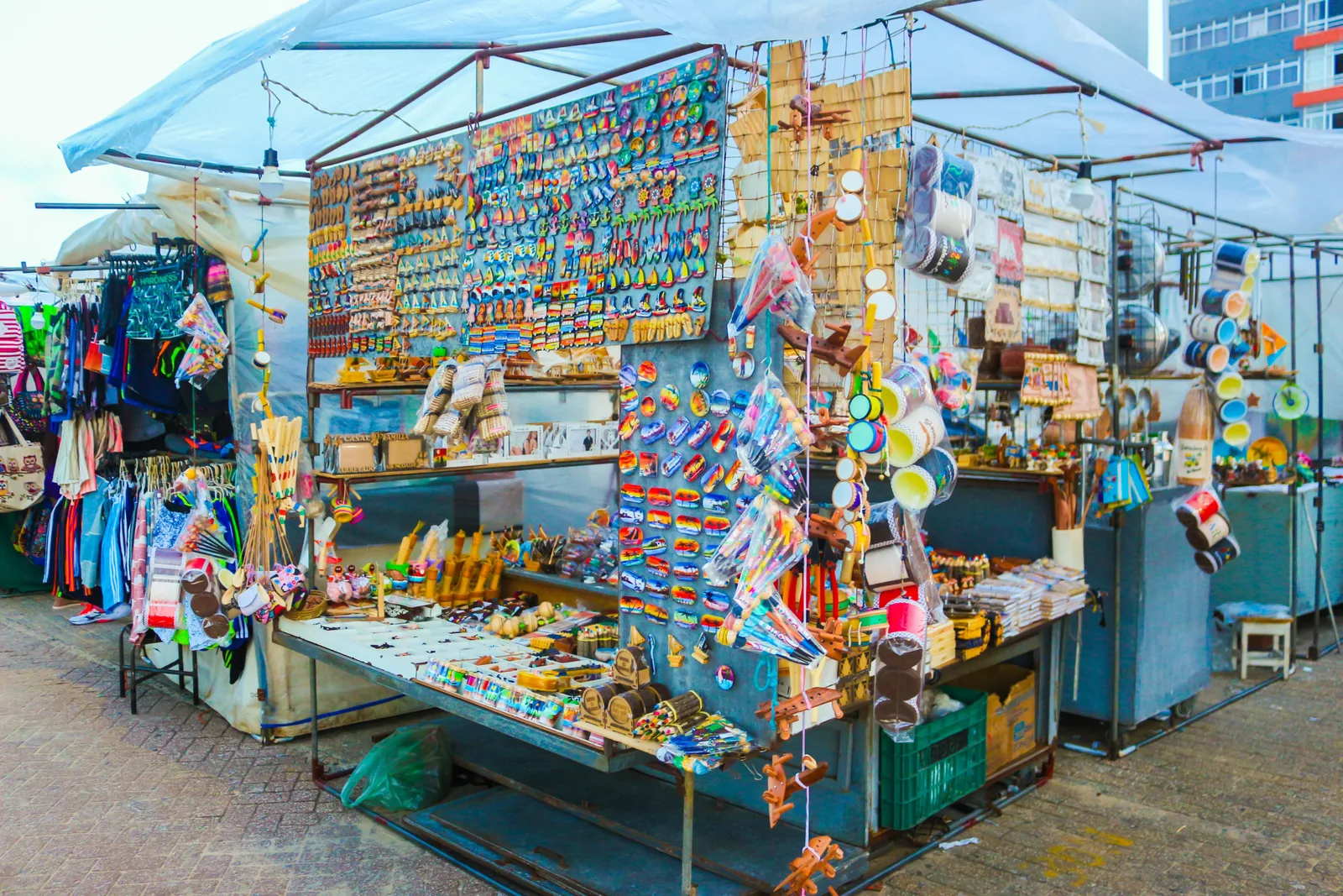 A craft-fair stall on the Beira Mar hung from top to bottom with painted souvenirs, hats and clothes, with trays of small goods laid out on the counter in front