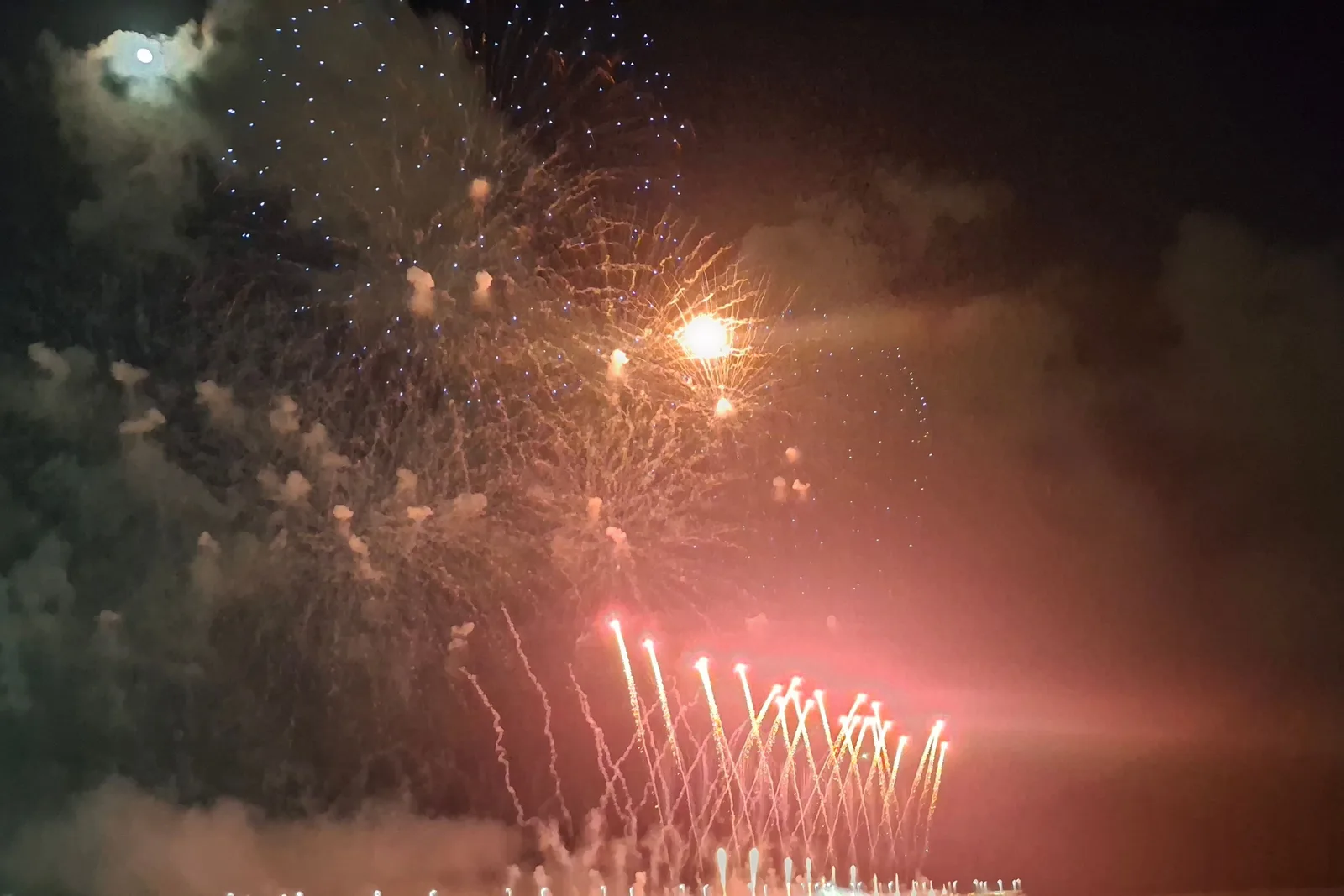 Fireworks bursting in gold and red over a dark crowd on the beach at Fortaleza on New Year’s Eve