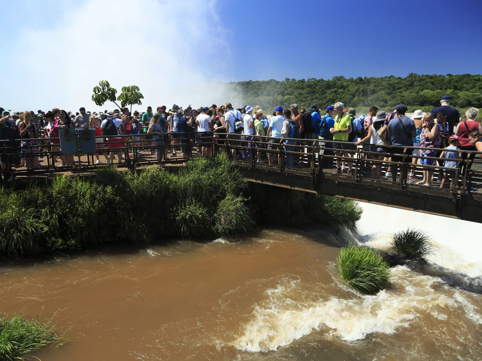 A crowd packed shoulder to shoulder along the walkway above the river at the Devil’s Throat, phones up over the railing