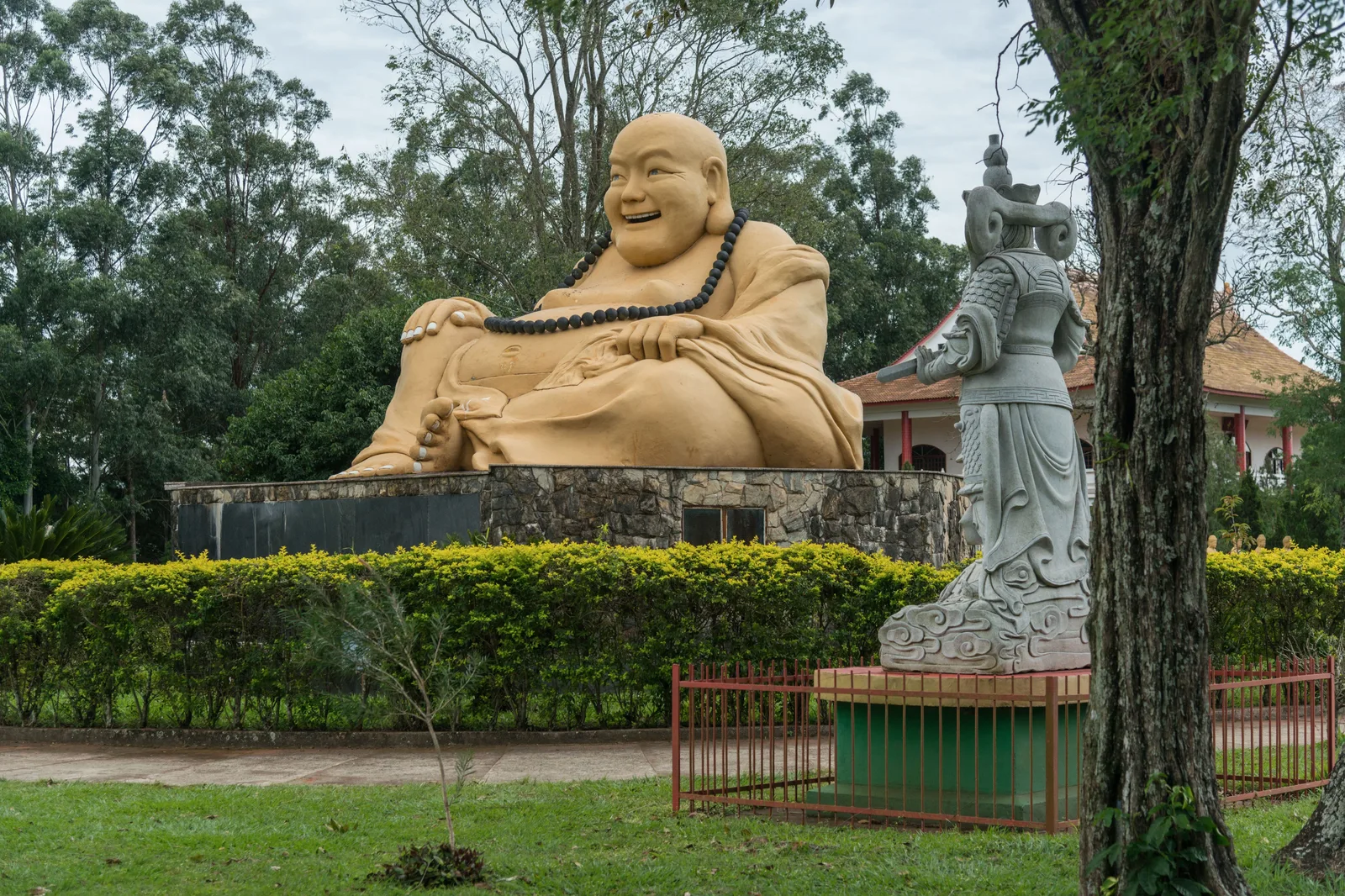 A large golden laughing Buddha statue in the gardens of the Buddhist temple in Foz do Iguaçu