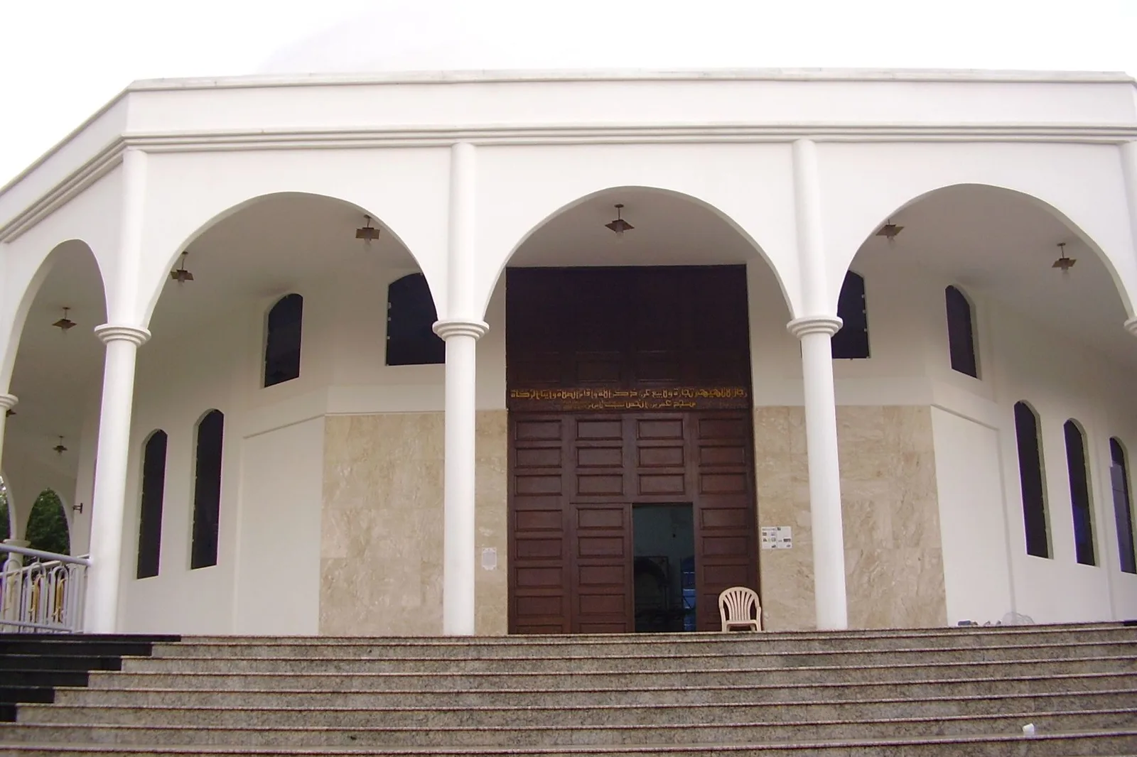 The arcaded white front of the Omar Ibn Al-Khattab mosque in Foz do Iguaçu, its columned porch and dark timber doors at the top of a short flight of steps