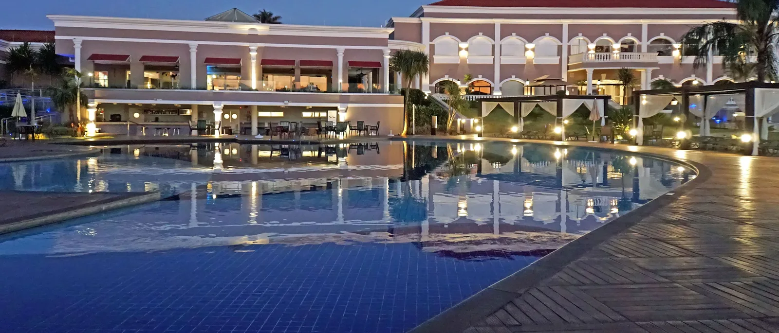 A resort pool on the road out to the falls at dusk, the lit front of the hotel reflected the length of the water