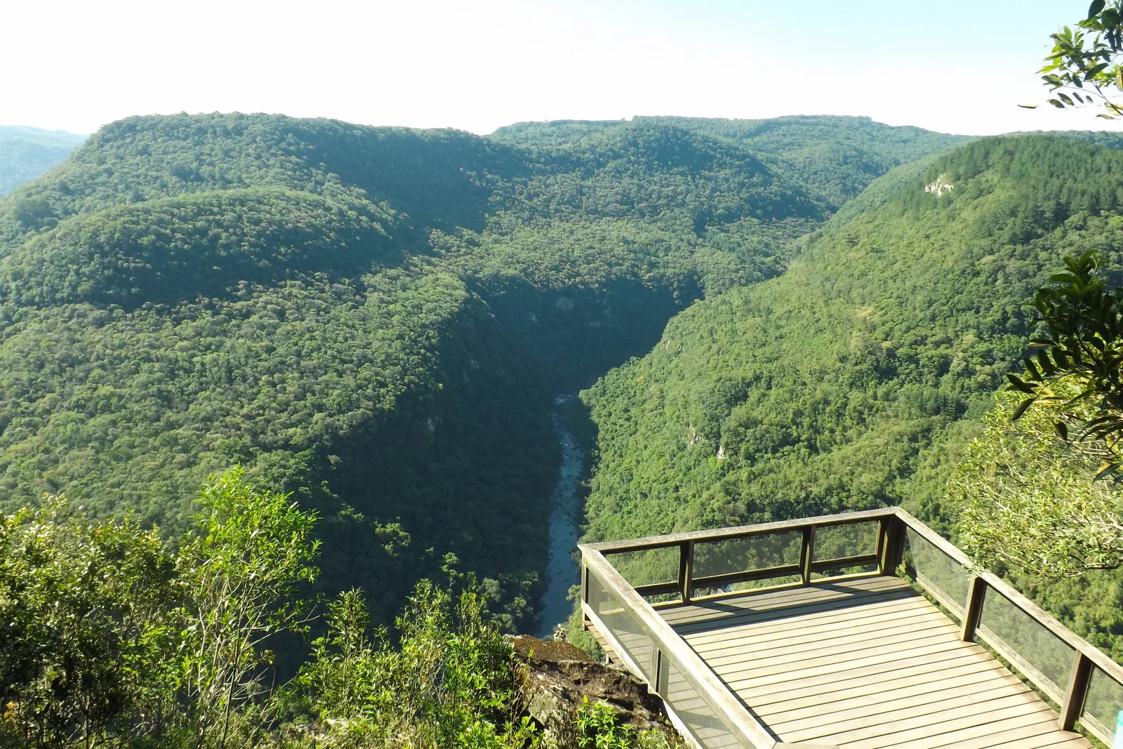 A wooden viewing deck on the rim of the Vale da Ferradura, looking out over steep forested slopes that fall into a deep canyon with a glimpse of river at the bottom