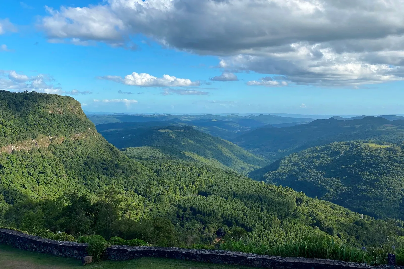 The Vale do Quilombo from above: forested slopes falling away into a long green valley with a flat-topped ridge on the left and hills fading into blue haze