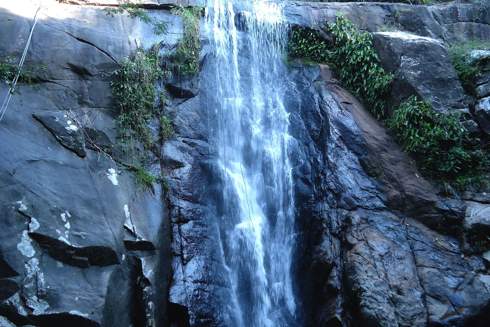 A waterfall dropping down a rock face into a pool at the foot of it, forest closing in on all sides