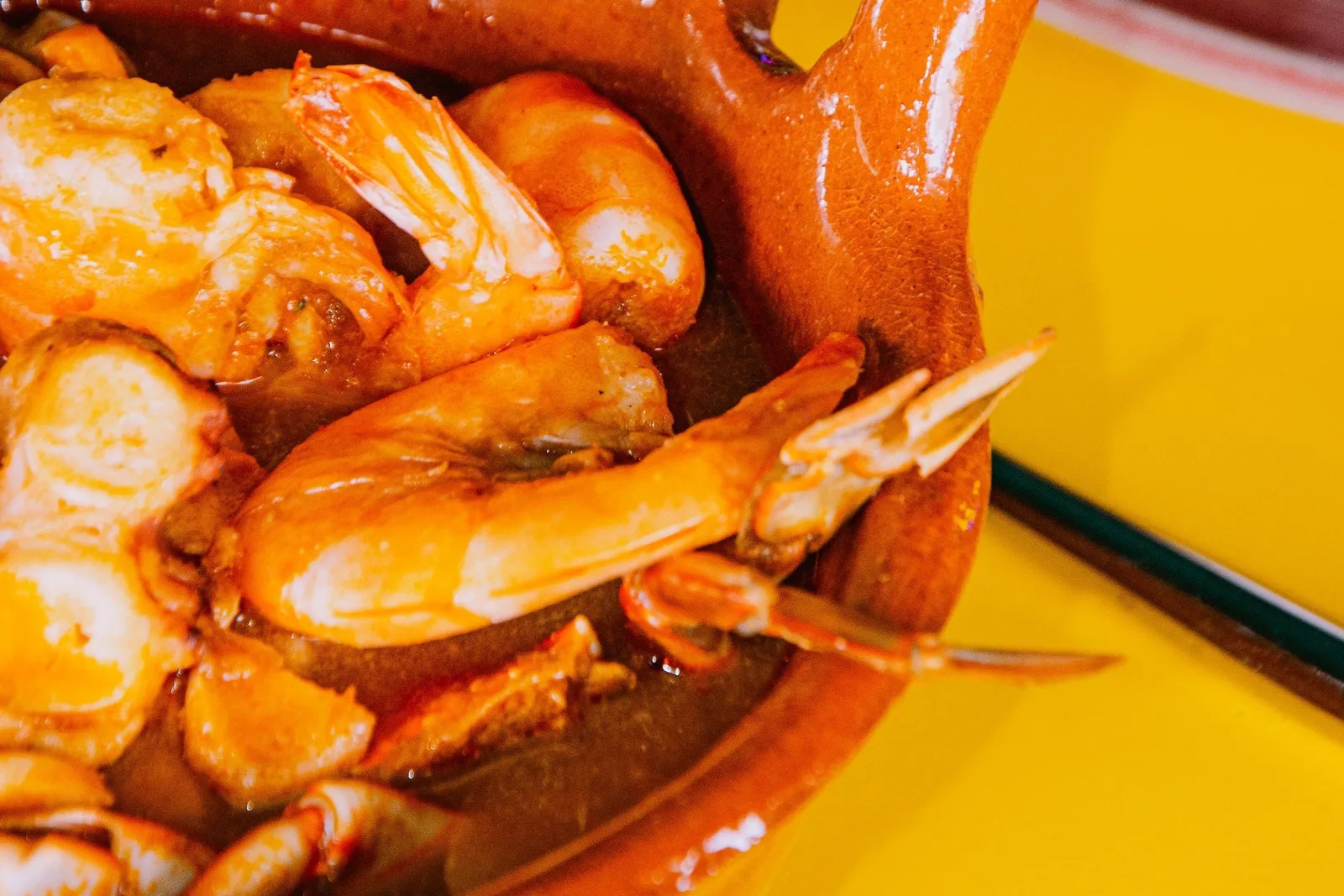A clay pot of seafood stew set down on a table