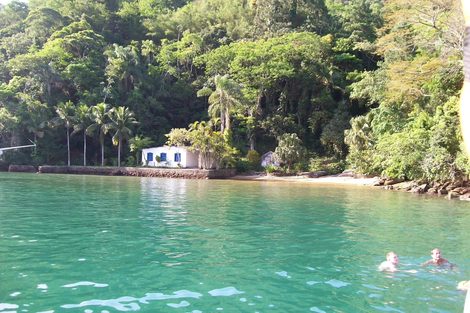 The almost-enclosed bay of the Saco do Céu, flat green water with forest running down to it and a house among the palms