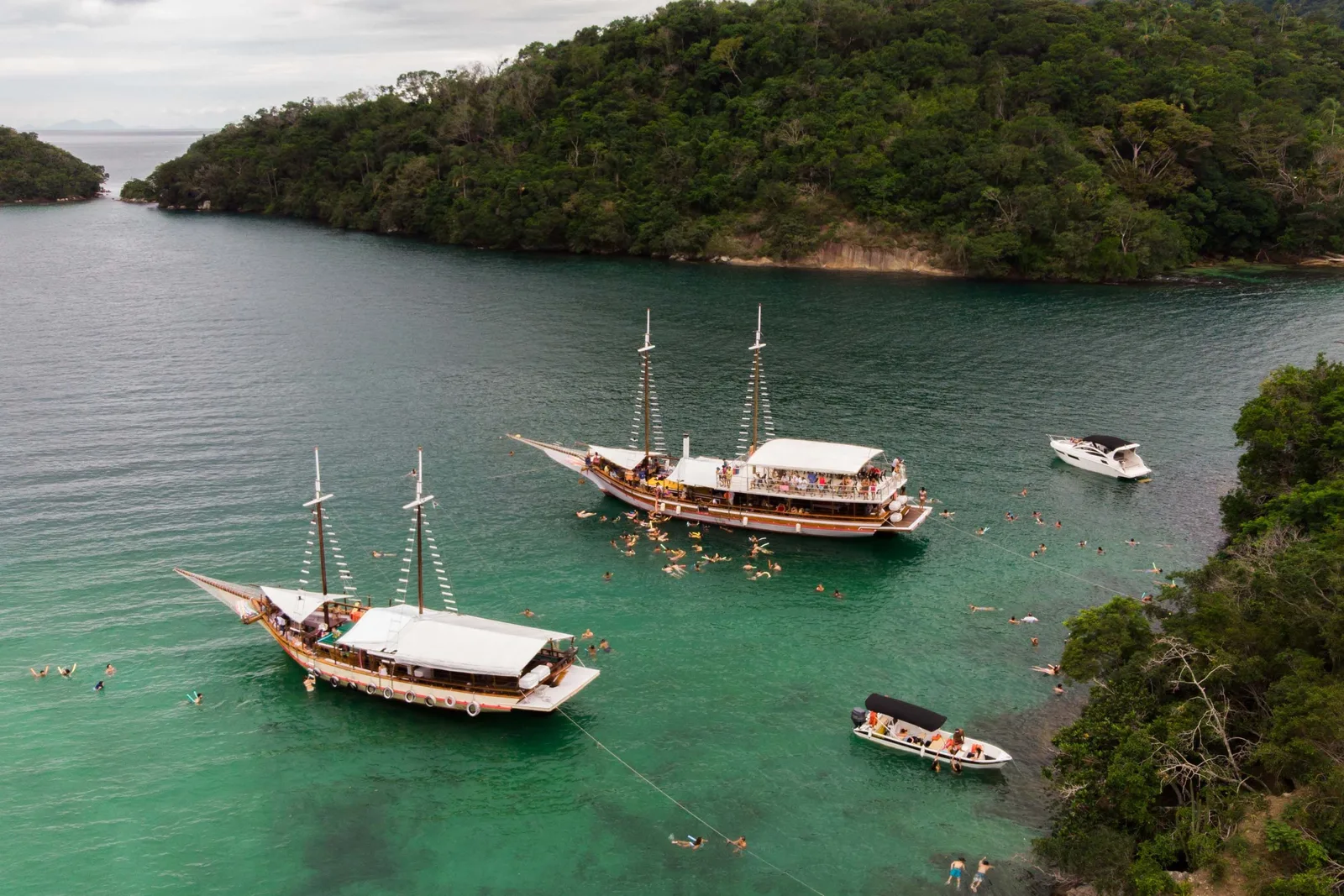 Schooners anchored in the green water of Lagoa Azul between forested islets