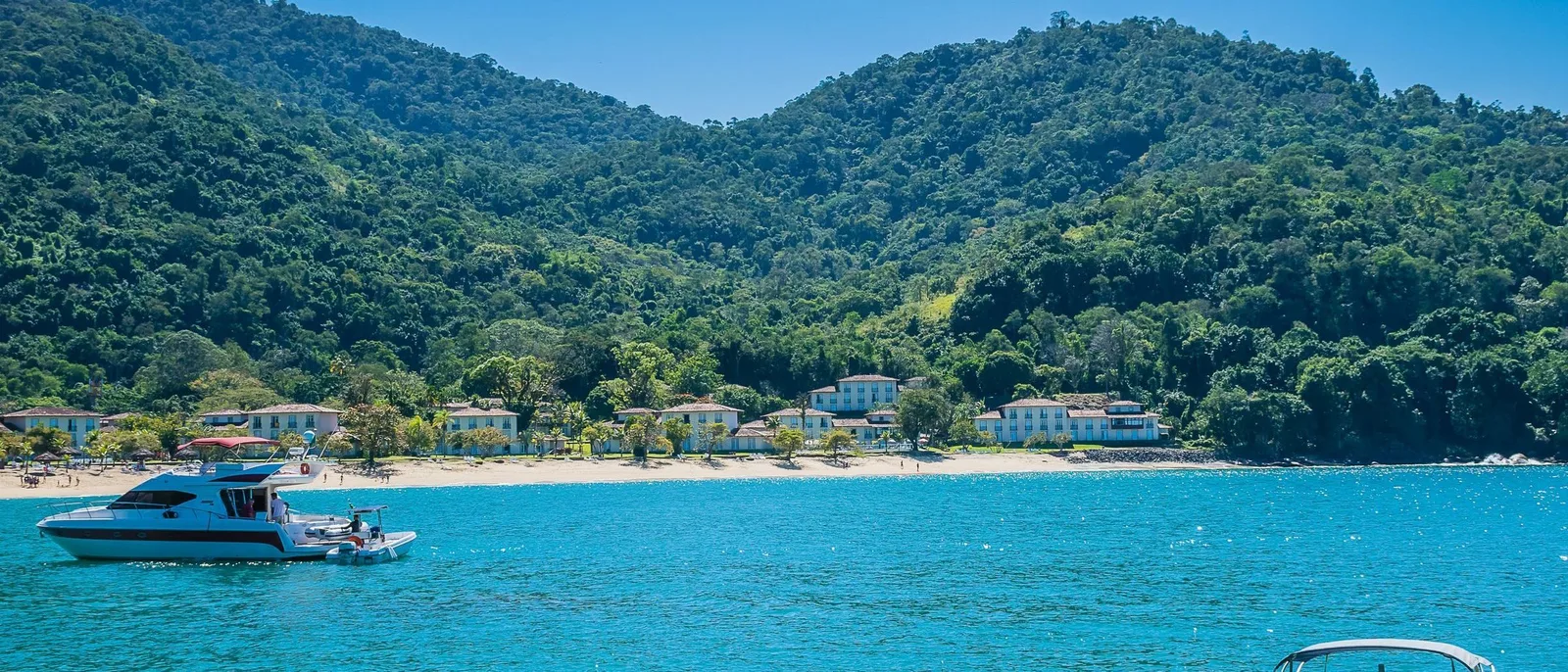Boats moored off Vila do Abraão with the village low along the shore and forested peaks rising behind it