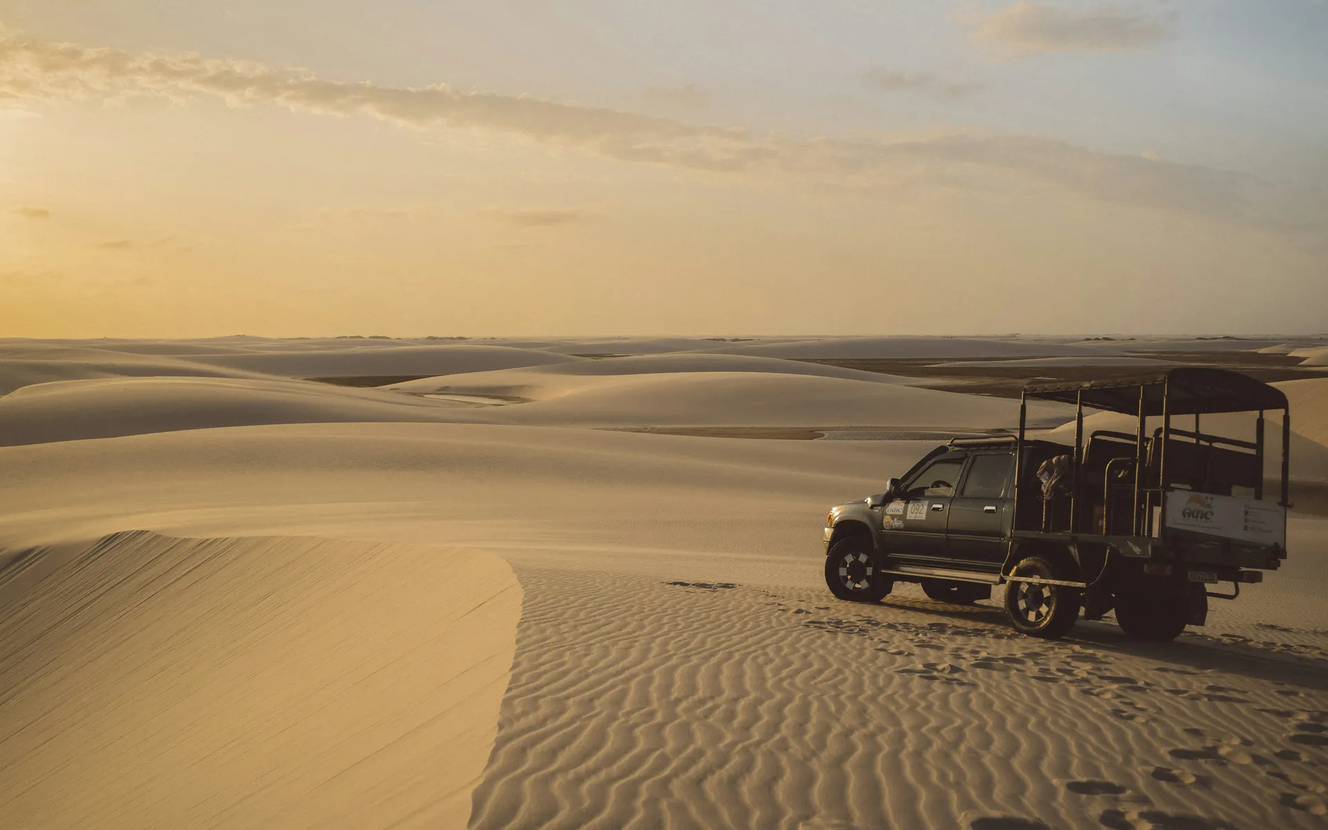A 4x4 crossing the dunes toward a lagoon in the Lençóis